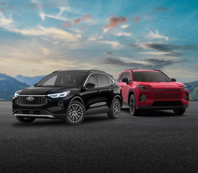 A black Ford Escape and a red Toyota RAV4 parked in front of a mountain background.