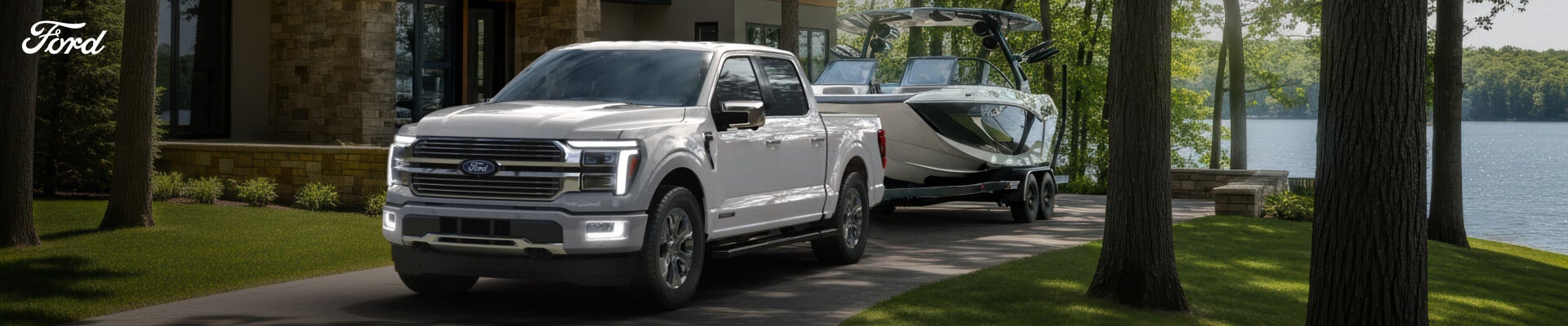 Front quarter view of a Ford F-150 Platinum towing a sport boat past a lakeside.